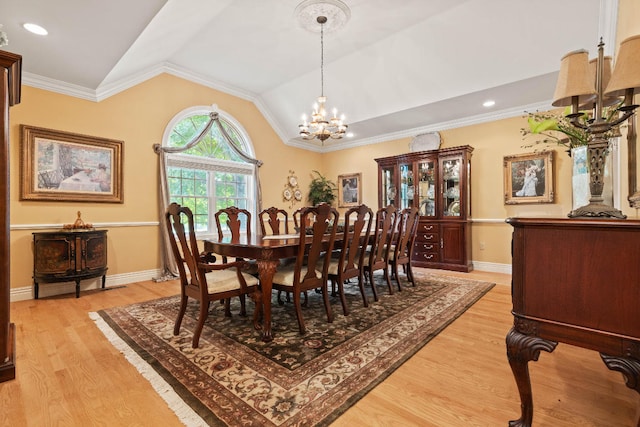 dining room with light hardwood / wood-style floors, crown molding, lofted ceiling, and a chandelier