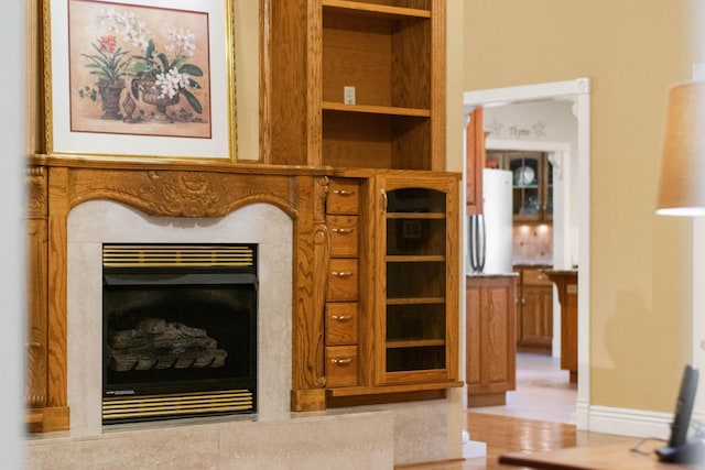 room details featuring freestanding refrigerator, a fireplace, and baseboards