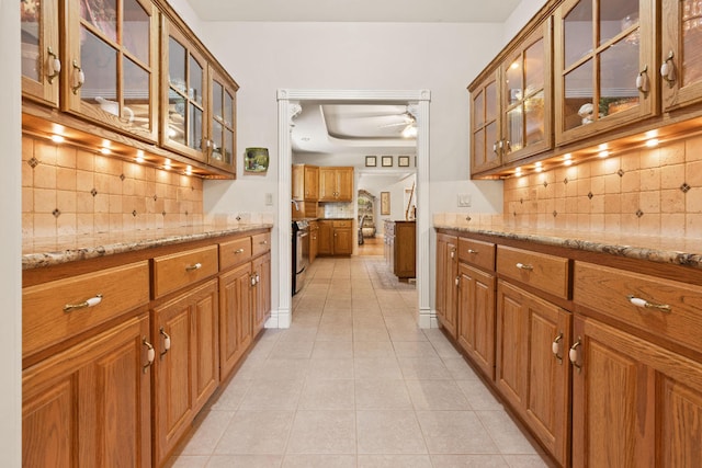 bar featuring stainless steel range with electric stovetop, light stone countertops, tasteful backsplash, and light tile patterned floors