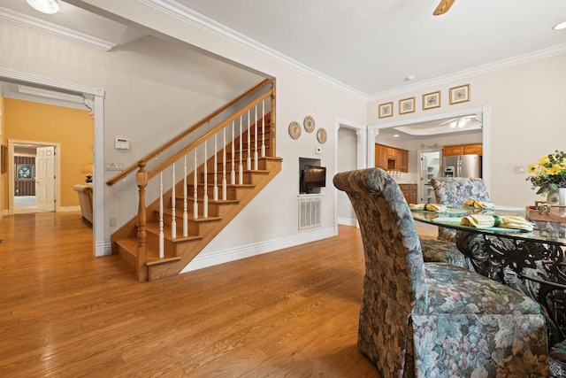 dining space with ornamental molding, light wood-style flooring, baseboards, and stairs