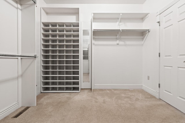 walk in closet featuring light colored carpet