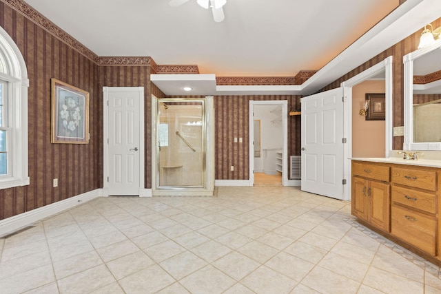 interior space with ensuite bathroom, light tile patterned flooring, and ceiling fan