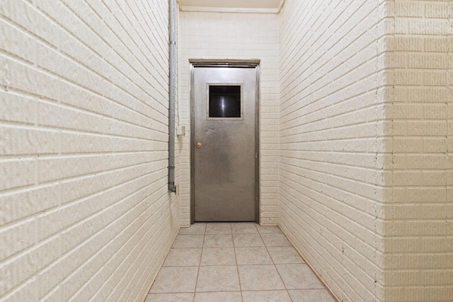 hallway featuring brick wall and light tile patterned floors