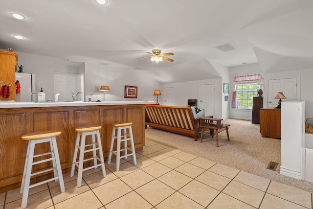 kitchen featuring light carpet, a breakfast bar, white fridge, and ceiling fan