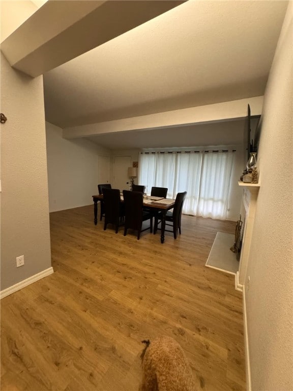 dining room featuring light hardwood / wood-style flooring and beamed ceiling