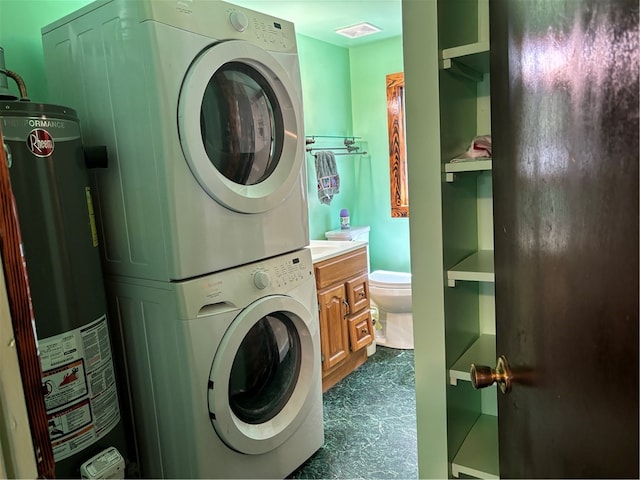 laundry room featuring gas water heater, cabinets, and stacked washer and dryer