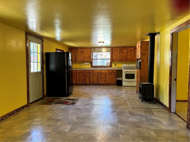 kitchen featuring black refrigerator, a wood stove, white range with gas stovetop, and sink