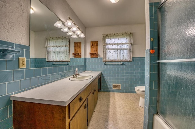 bathroom with a shower with shower door, visible vents, toilet, tile walls, and vanity