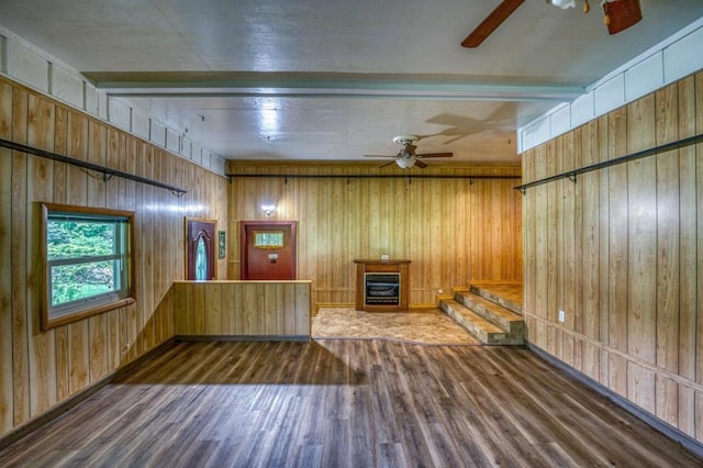 unfurnished living room featuring wooden walls, ceiling fan, stairway, a fireplace, and wood finished floors