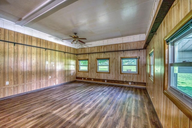 spare room featuring wood walls, ceiling fan, and wood finished floors