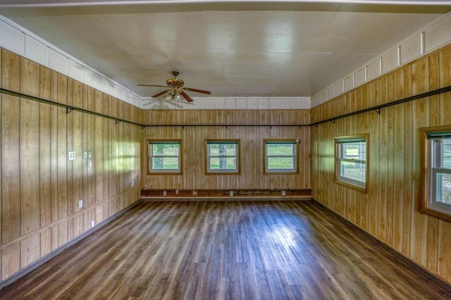 spare room featuring ceiling fan, wooden walls, and wood finished floors