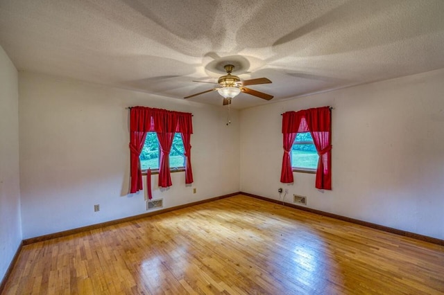 empty room featuring visible vents, baseboards, a textured ceiling, and hardwood / wood-style flooring