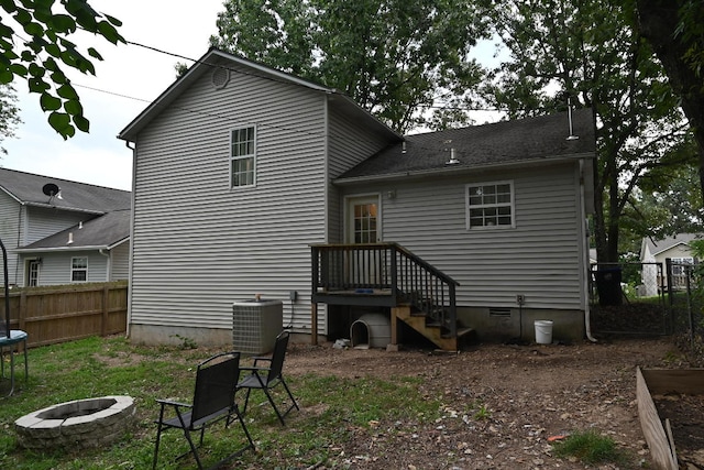 rear view of property featuring an outdoor fire pit and central AC