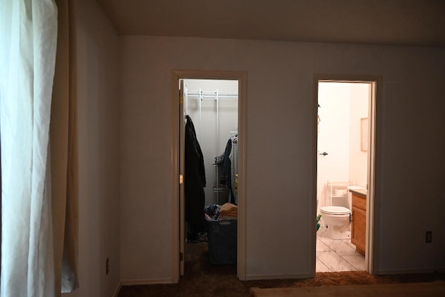 bedroom featuring a walk in closet, connected bathroom, a closet, and tile patterned floors