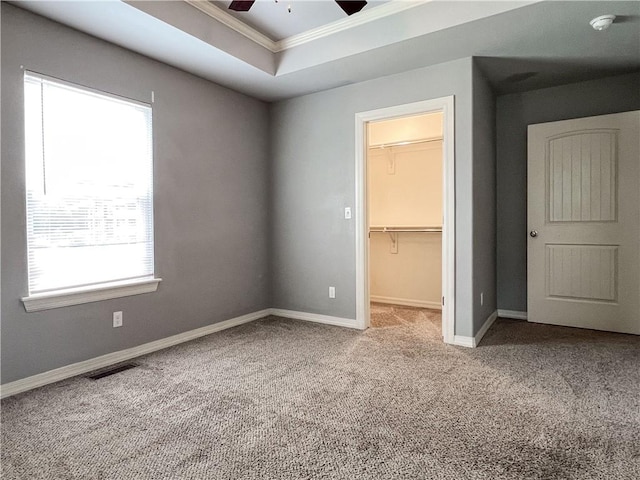 unfurnished bedroom featuring a raised ceiling, visible vents, a spacious closet, carpet flooring, and baseboards