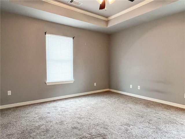 unfurnished room with visible vents, a ceiling fan, a tray ceiling, crown molding, and carpet floors