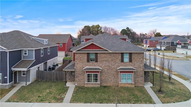 traditional-style home featuring a residential view, roof with shingles, fence, and a front lawn