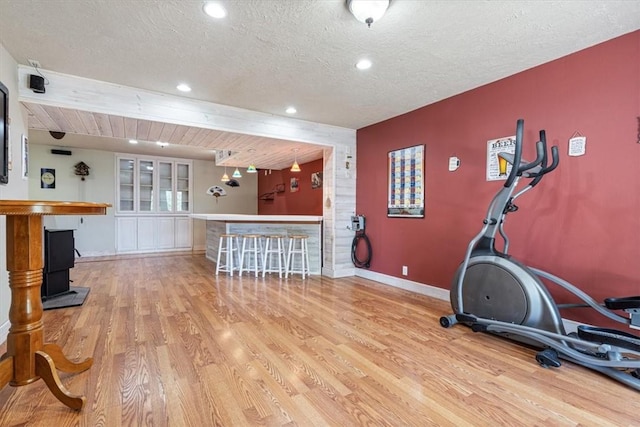 workout room featuring baseboards, a dry bar, recessed lighting, wood finished floors, and a textured ceiling