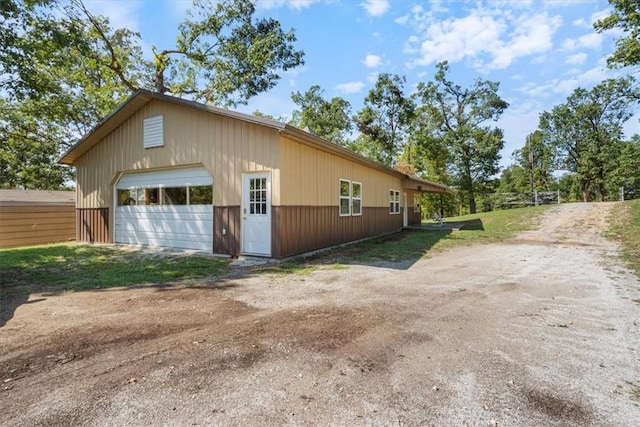 view of side of home with a garage, an outdoor structure, and dirt driveway