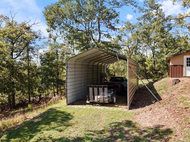 view of outdoor structure with a detached carport and driveway