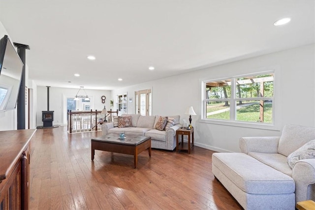 living area with recessed lighting, a wood stove, baseboards, and wood-type flooring