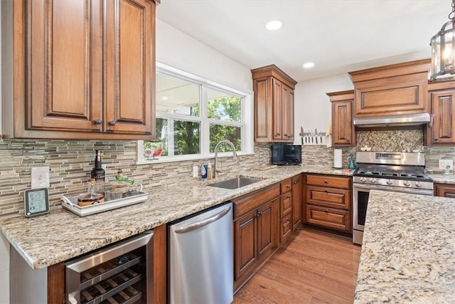 kitchen featuring beverage cooler, a sink, decorative backsplash, stainless steel appliances, and light wood-style floors