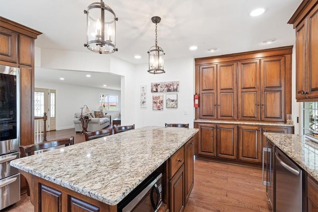 kitchen featuring light wood-style flooring, recessed lighting, stainless steel appliances, light stone countertops, and hanging light fixtures