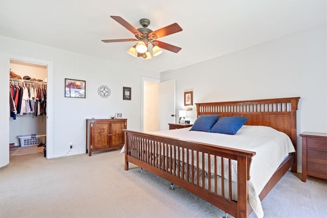 carpeted bedroom featuring a closet, a walk in closet, and a ceiling fan