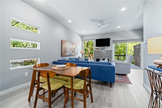 dining space with light wood-type flooring, a brick fireplace, baseboards, and recessed lighting