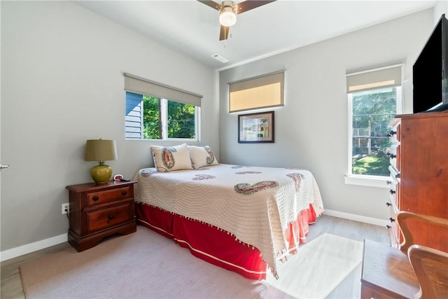 bedroom featuring a ceiling fan, multiple windows, visible vents, and baseboards