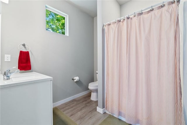 full bath featuring baseboards, toilet, a shower with curtain, wood finished floors, and vanity