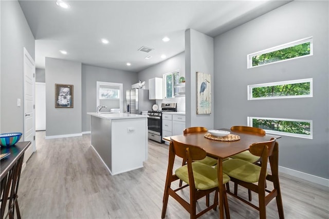 kitchen with white cabinets, a center island with sink, stainless steel appliances, and a wealth of natural light