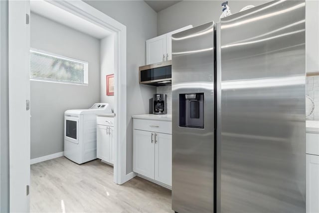 kitchen with light countertops, appliances with stainless steel finishes, white cabinetry, washer / dryer, and light wood-type flooring