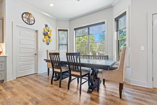 dining area featuring crown molding, light hardwood / wood-style flooring, and a healthy amount of sunlight