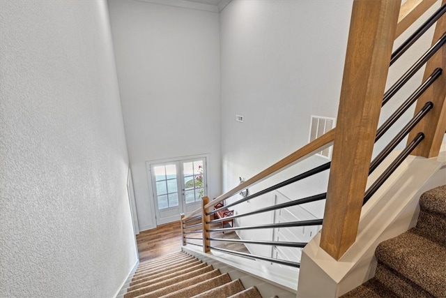 stairs featuring a high ceiling, wood-type flooring, and french doors