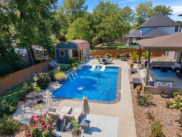 view of pool featuring an outdoor living space, a patio, pool water feature, and an outbuilding