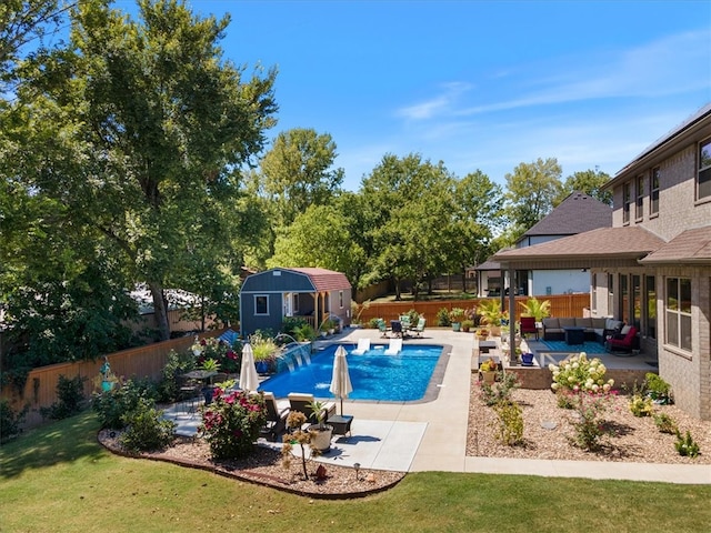 view of pool with a patio, an outdoor hangout area, pool water feature, a yard, and a shed