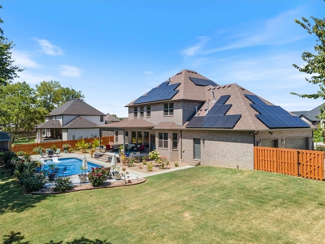 back of property featuring a lawn, solar panels, a fenced in pool, and a patio