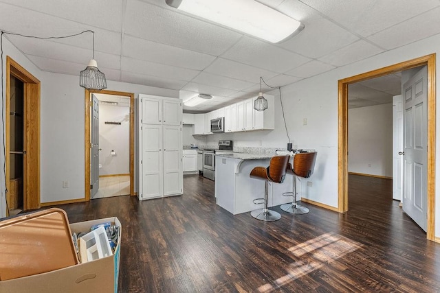 kitchen featuring pendant lighting, white cabinets, a kitchen bar, kitchen peninsula, and stainless steel appliances