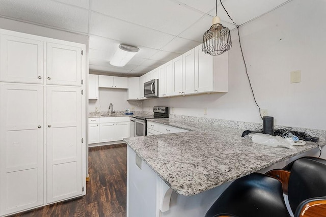 kitchen featuring white cabinetry, stainless steel appliances, a kitchen breakfast bar, decorative light fixtures, and kitchen peninsula