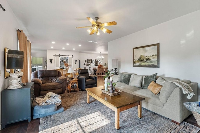 living room with dark hardwood / wood-style flooring, a barn door, and ceiling fan