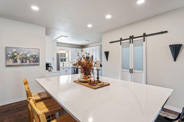 dining space featuring sink, dark wood-type flooring, and a barn door