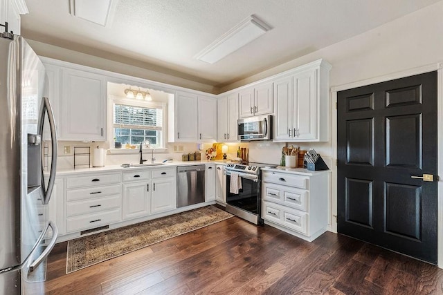 kitchen featuring stainless steel appliances, dark hardwood / wood-style floors, sink, and white cabinets