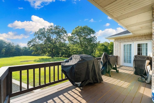 wooden terrace featuring a grill and a lawn