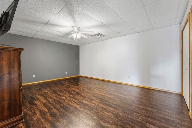 empty room with dark wood-type flooring, a paneled ceiling, and ceiling fan