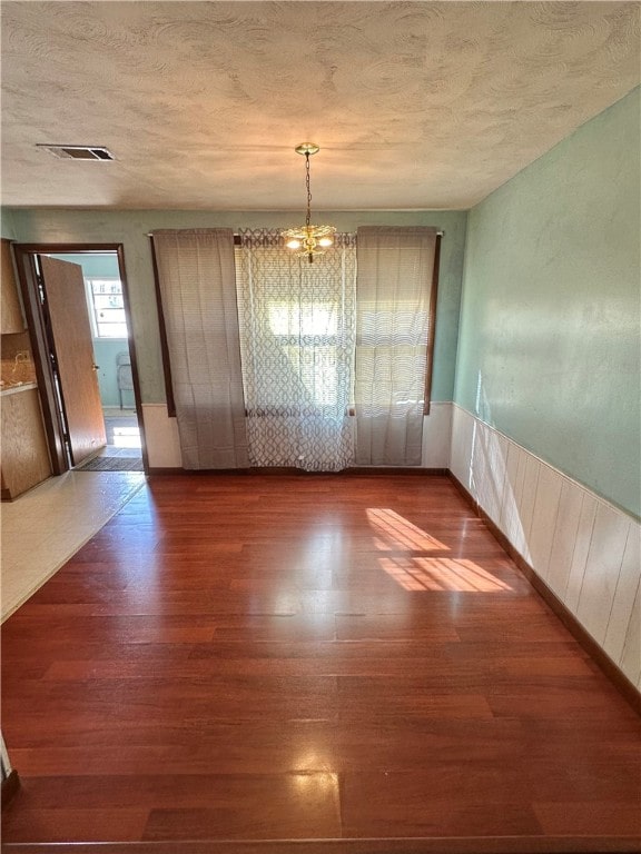 unfurnished dining area featuring hardwood / wood-style flooring and a notable chandelier