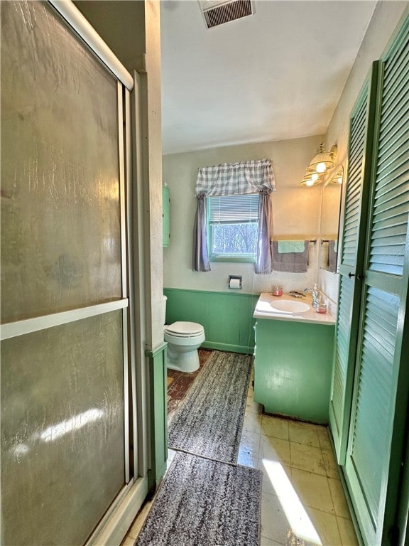 bathroom featuring tile patterned flooring, a shower with door, vanity, and toilet