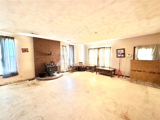 unfurnished living room with a wealth of natural light, brick wall, and a wood stove