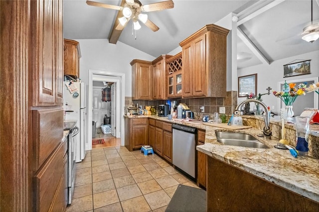 kitchen featuring light stone counters, stainless steel appliances, lofted ceiling with beams, decorative backsplash, and a sink