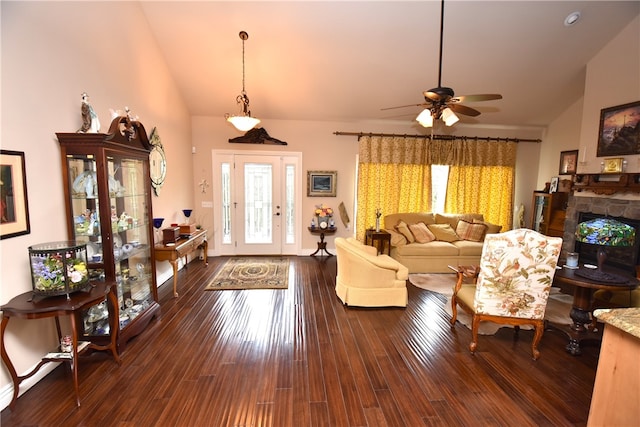 living room with ceiling fan, vaulted ceiling, dark hardwood / wood-style floors, and a stone fireplace